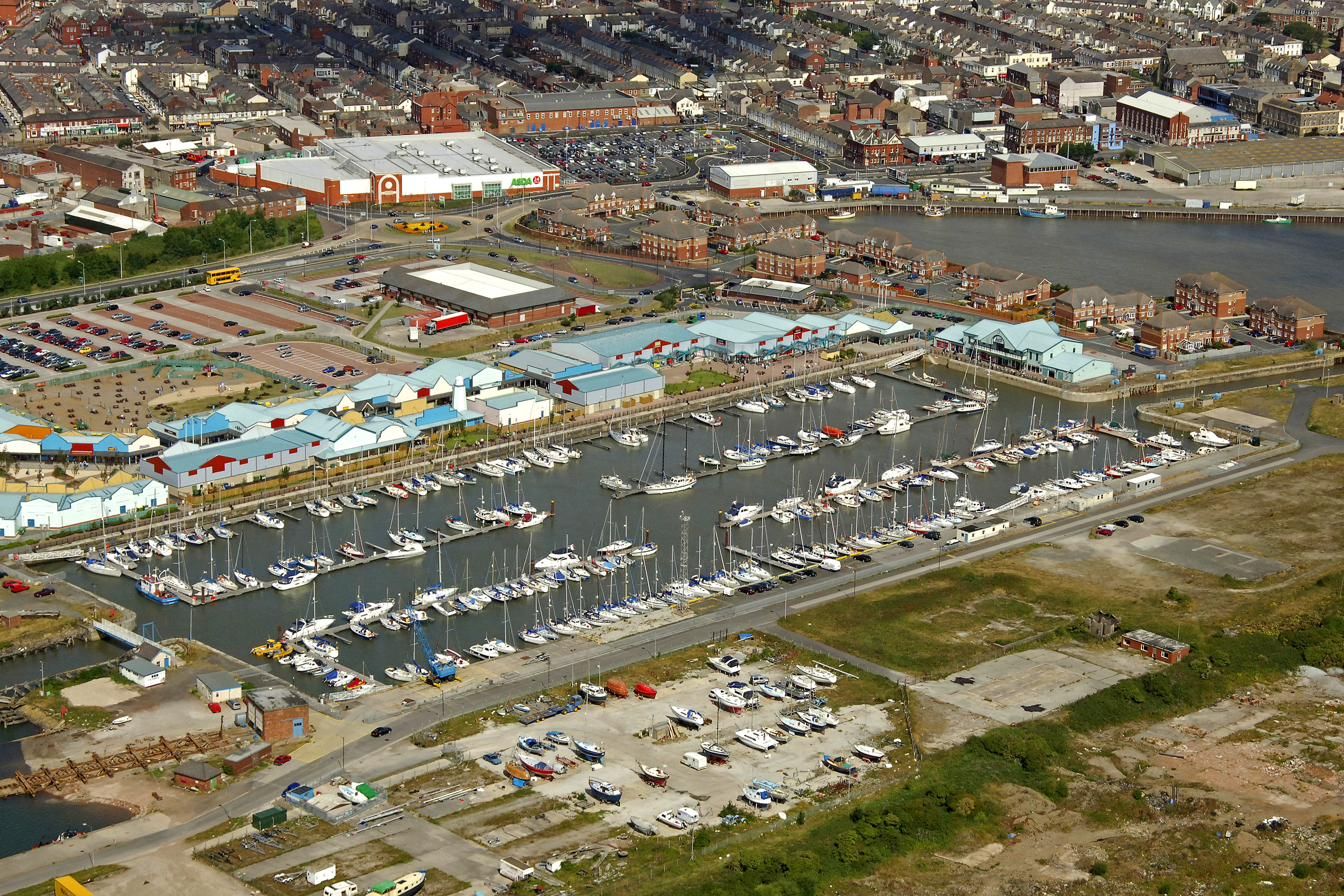 Aerial view along Fleetwood marina showing boats on the pontoons, the hoist on the quay and boats laid up on the hardstanding beside the dock
